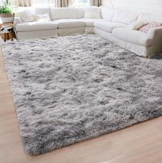 a living room with a large rug on the floor and white couches in it