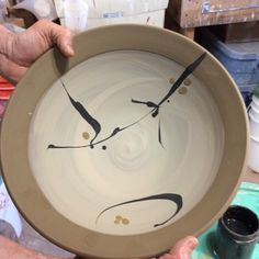 a person holding a bowl with black and white designs on it