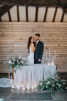 a bride and groom standing next to each other in front of a table with candles