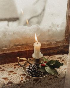 a lit candle sitting on top of a glass plate next to a window sill