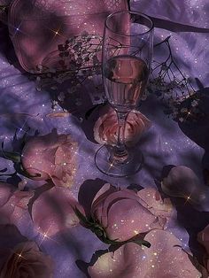 pink roses and wine glasses are on a purple tablecloth with stars in the background