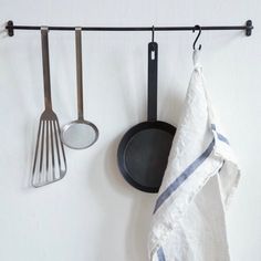 kitchen utensils hanging on a wall next to a towel and spatulas