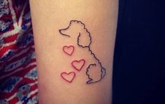 a woman's arm with a dog and hearts tattoo on it