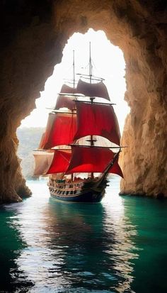 a large red sail boat sailing through a cave