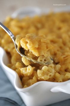 a spoon full of macaroni and cheese in a white dish