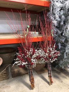 three vases with red berries and white flowers in them next to a christmas tree