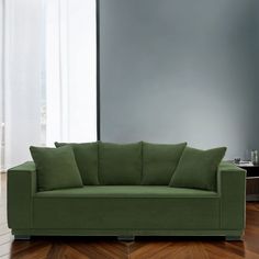 a green couch sitting on top of a hard wood floor