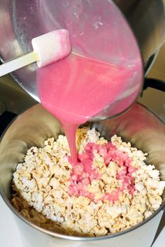 a person pouring pink liquid into a pot full of food