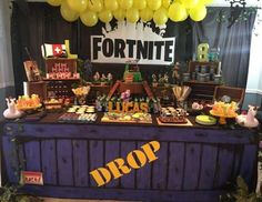 a table topped with lots of desserts and balloons in front of a fortnite sign