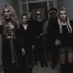 a group of people standing in a hallway with one woman holding a cane and the other is looking at the camera