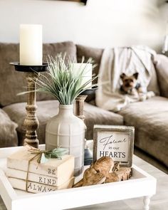 a coffee table with books, candles and a vase on it