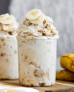 two desserts with banana slices and whipped cream in them sitting on a table next to bananas