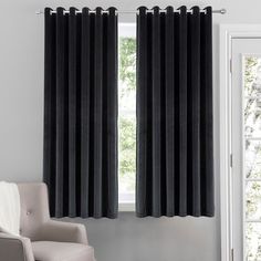 a living room with black curtains and a chair