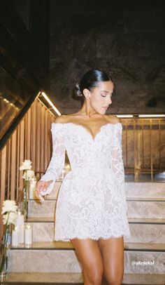 a woman in a white dress is walking down the stairs with her hand on her hip