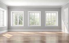 an empty room with three windows and hard wood floor