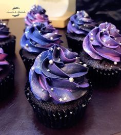 some cupcakes with purple frosting and stars on them are sitting on a table