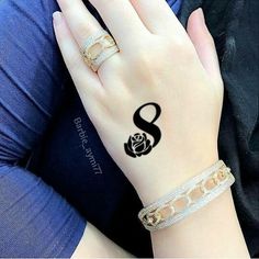 a woman's hand with a rose tattoo on her left wrist and two gold rings