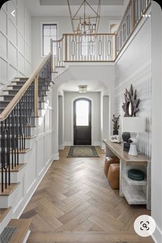 an entryway with wood floors and white walls, wooden stairs leading up to the second floor