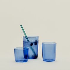 three blue glass cups with one drinking straw