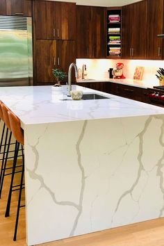 a kitchen with an island counter top and bar stools in front of the sink