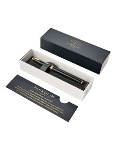 an open box with a pen in it on a white surface next to a black and gold package