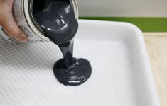 a person pouring blue paint onto a white tray