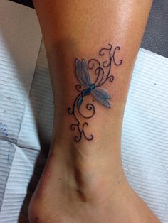 a woman's foot with a blue dragonfly tattoo on the bottom of it