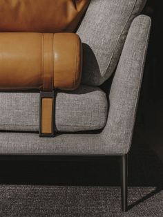 a brown leather pillow sitting on top of a grey couch next to a gray chair