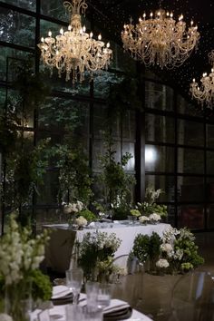 a dining room with chandeliers hanging from the ceiling and tables covered in white linens