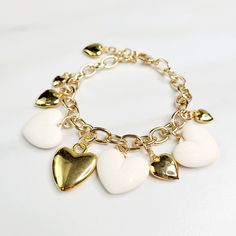 Vintage hearts are the focal point of this love filled bracelet. An assortment of gold plated hearts and matte ivory hearts play along the edge, perfect as a gift for someone you love. Handmade in the United States, a matching necklace and earring set are available. Features: - Gold Plated Vintage Hearts - Matte Ivory Vintage Hearts - Gold Plated Mixed Cable Chain - Lobster Claw Clasp - Extension - Handmade in the United States Dimensions: - Length: 7.5" - Extension: 1" - Total Length: 8.5" White Heart-shaped Metal Charm Bracelet, White Metal Heart Bracelet, White Metal Heart-shaped Bracelet, Elegant White Charm Bracelet With Heart Charm, Elegant White Heart Bracelet For Valentine's Day, Elegant White Heart Charm Bracelet, White Heart Charm Bracelet For Anniversary, Gold Metal Charm Bracelet With Heart Beads, White Heart-shaped Jewelry Gift For Her