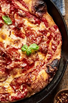 a pizza sitting on top of a pan covered in cheese and sauce next to a bowl of seasoning