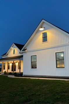 a large white house sitting on top of a lush green field under a blue sky