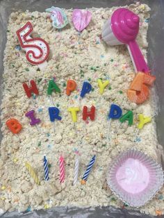 a birthday cake with candles and decorations on it's side in a plastic container