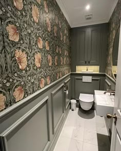 a bathroom with floral wallpaper and white toilet next to sink in the middle of the room