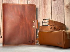 a brown leather book and belt are sitting next to each other on a wooden surface