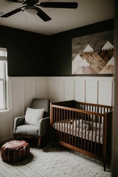 a baby's room with a chair, crib, and painting on the wall