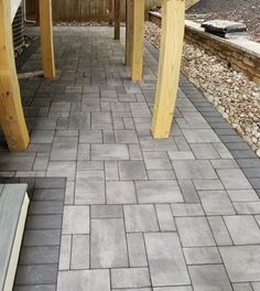 an outdoor walkway with wooden posts and brick pavers on either side, leading to the back yard