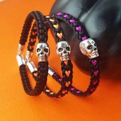 This Halloween skull bracelet is woven in a Kumihimo style flat braid with 1mm thick nylon satin thread in black/orange mix, black/purple mix or solid black.  Custom colors are available if requested. It includes a silver scary skull bead spacer charm, with a matching silver hook clasp. If you would like to create this bracelet in your own custom colors please send me a message. See color chart in last listing photo. it is available in 7 Lengths: (XS) 6inches (fits 5-5.5inch wrist) (S)  6.5inches (fits 5.5-6inch wrist) (M) 7inches (fits 6.5-7inch wrist) (L)  7.5inches (fits 7-7.5inch wrist) (XL) 8inches (fits 7.5-8inch wrist) (XXL) 8.5inches (fits 8-8.5inch wrist) (XXXL) 9inches (fits 8.5-9inch wrist) Perfect for any Halloween costume, or Spooky Season party gift! Many thanks, and have a w Adjustable Black Leather Bracelet For Halloween, Adjustable Black Bracelets For Halloween, Black Skull Bracelets For Festival, Handmade Black Paracord Braided Bracelet, Handmade Black Skull Bracelets, Handmade Black Skull Bracelet, Scary Skull, Halloween Bracelet, Skull Bracelet