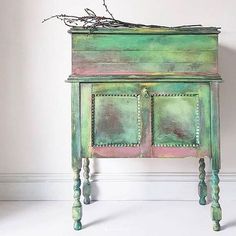 an old green painted cabinet with some branches on top and one branch sticking out of it