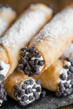 chocolate chip covered pastry rolls on a plate with powdered sugar and sprinkles