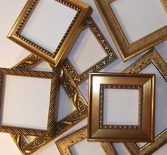 several gold colored frames are arranged on a white wall, with one empty square in the middle