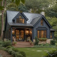 a blue house with lots of windows and steps leading up to the front door is surrounded by greenery