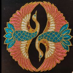 an intricately designed peacock design on a black surface with blue and pink feathers in the center