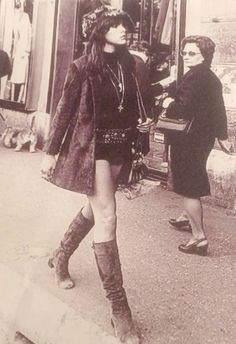 an old photo of two women walking down the street with one woman wearing boots and hat