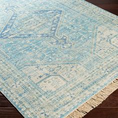 a blue and white area rug with fringes on the bottom, sitting on a wooden floor