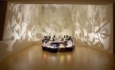 two vases sitting on top of a wooden floor in front of a projected wall