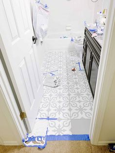 a bathroom that is being remodeled with blue tape on the floor and toilet in the background