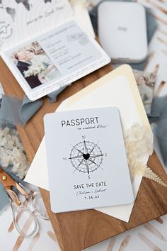 an open passport sitting on top of a wooden table next to other papers and glasses