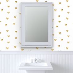 a white sink sitting under a mirror next to a wall mounted faucet with gold hearts on it