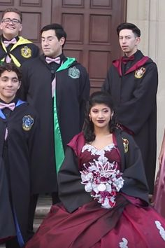 a group of people dressed in gowns posing for a photo on the steps of a building